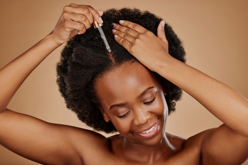 phot of women using sate haircare hair growth oil on her scalp to stop hair loss